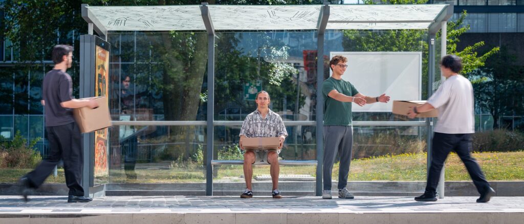 QuTech PhD candidates at a bus stop, symbolising how the moving qubit travels between stops on the chip to collect and deliver quantum information.